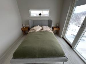 a bed in a small room with two windows at Brúarárbyggð B1 in Blaskogabyggo