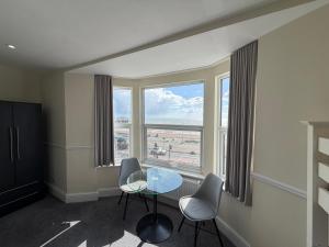 a room with a table and chairs and a large window at The Brighton Hotel Seafront in Brighton & Hove