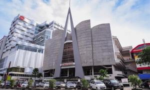 a large building with cars parked in front of it at Rumah Cluster Springwood1 in Pontianak