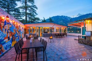 a patio with tables and chairs and a mural at Zostel McLeodganj in McLeod Ganj