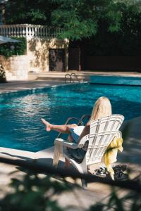 a woman sitting in a chair next to a swimming pool at Auberge du Rédier - Logis Hôtels in Colomars +14 photos
