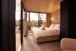 a bedroom with a bed and a large window at HANNAH Mirror Tiny House in Den Bosch