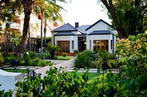a house with a garden and palm trees at Cecil John Rhodes Guest house in Kimberley