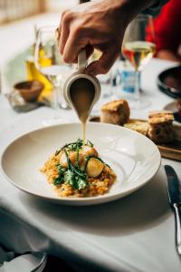 a person is pouring sauce on a plate of food at Auberge du Rédier - Logis Hôtels in Colomars