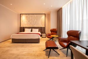 a hotel room with a bed and a table and chairs at ZUMMA Hotel Almaty in Almaty