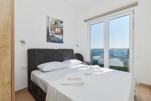 a bedroom with a white bed with a large window at Adriatic Heights Holiday Apartments in Kavač +19 photos