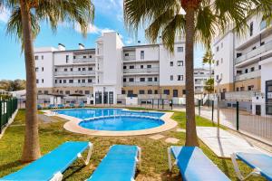 a swimming pool with palm trees in front of a building at Las Dunas 213 - by Welcomely in Oliva
