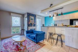 a living room with a blue couch and a kitchen at Chambre d'Amour Jacuzzi Bordeaux Parking in Bruges