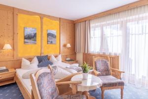 a bedroom with a bed and a table and chairs at Bergidyll & Hotel Trofana in Leutasch