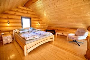 a bedroom with a bed and a chair in a log cabin at Golden Log House in Hajdúszoboszló