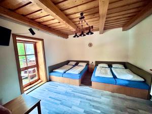 a bedroom with two beds and a table and a window at Chatka pod orechom in Terchová
