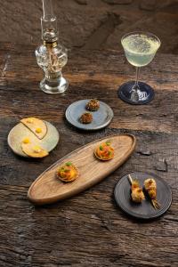 a wooden table with plates of food and a drink at La Chaumée par L'émulsion in Saint-Alban-de-Roche