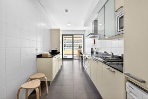a kitchen with white cabinets and stools in it at Aquamar Pro 116 in Quarteira