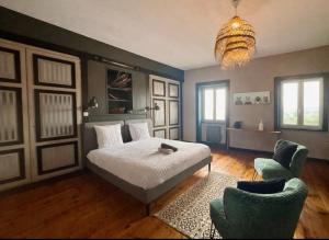 a bedroom with a bed and two chairs and a chandelier at O Beaujolais Chiroubles in Chiroubles