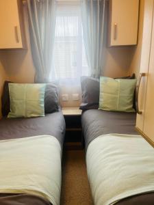 two beds in a small room with a window at Calypso Hot Tub Breaks Tattershall Lakes Pet Friendly in Tattershall +22 photos