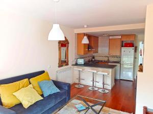 a living room with a blue couch and a kitchen at Apartamentos Las Margas Sabiñánigo 3000 in Sabiñánigo