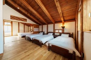 four beds in a room with wooden ceilings and wood floors at NEKO no TSUKI in Takayama