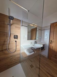 a bathroom with a shower with a sink and a mirror at Ferienwohnungen Kuentnerhof in San Candido +112 photos