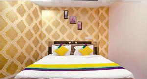 a bedroom with a large white bed with yellow and colorful pillows at Hotel Qness in Hyderabad