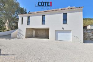 a white house with two garage doors and a driveway at Villa Concept in Ensuès-la-Redonne