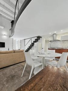 a dining room and living room with a white table and chairs at La Via della Giudecca in Syracuse