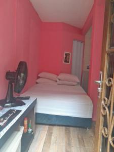 a bedroom with a bed with red walls and a desk at Hospedagem Mariano in Arraial do Cabo +1 photo