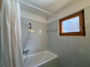 a bathroom with a tub and a shower with a window at Fontannets 001 COSY & MOUNTAIN chalet 10 pers in Veysonnaz +27 photos