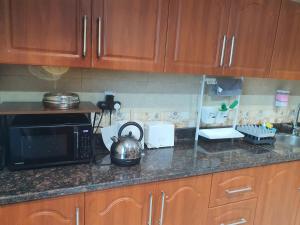 a kitchen counter with a microwave and a tea kettle at Stylish 2 BR Apartment in Ajman Residences Tower 4 in Ajman  +12 photos
