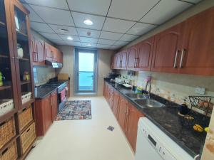 a large kitchen with wooden cabinets and a sink at Stylish 2 BR Apartment in Ajman Residences Tower 4 in Ajman 