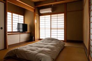 a bedroom with a bed and a tv and windows at Bunkyo in Naoshima
