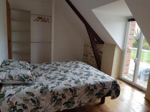 a bedroom with a bed with a comforter and a window at Gîte des Gatinelles in Erbray