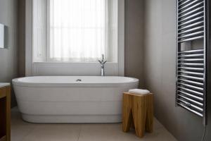 a white bath tub in a bathroom with a window at Tigerlily in Edinburgh