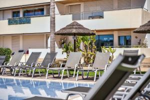 a row of chairs and umbrellas next to a swimming pool at Aquamar Pro 116 in Quarteira