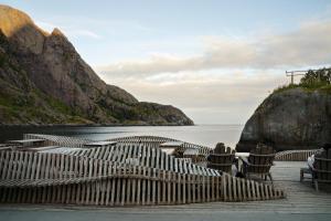 a view of a beach with chairs and the water at Lofoten Cottages by Nusfjord in Nussfjord +64 photos
