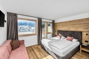 a bedroom with a white bed and a pink couch at Hotel Panorama in San Martino di Castrozza +154 photos