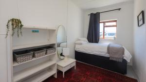 a small bedroom with a bed and a window at 206 On Main in Agulhas