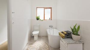a white bathroom with a tub and a toilet at 206 On Main in Agulhas +25 photos