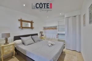 a white bedroom with a bed and a night stand at A La Vaquera - Gîte équestre in Châteauneuf-lès-Martigues