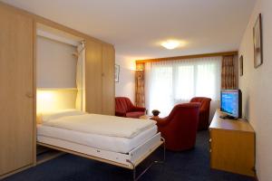 Una habitación de hotel con una cama y un escritorio con televisión. en Bolero Appartements, en Zermatt