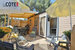 a deck with chairs and a table and an umbrella at Lou Soleil - Bungalow - 6 couchages in Carry-le-Rouet