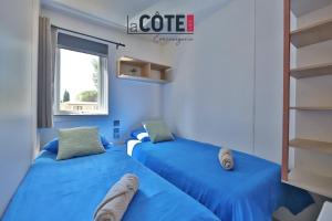 two blue beds in a room with a window at Lou Soleil - Bungalow - 6 couchages in Carry-le-Rouet