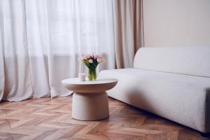 a vase of flowers on a table next to a bed at Bohemian in Šamorín