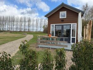 a tiny house with a porch and a table at De Ree Tiny House Tussen de Dijken in Driewegen