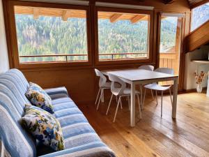 a living room with a couch and a table and windows at Mansarda vista lago in Auronzo di Cadore