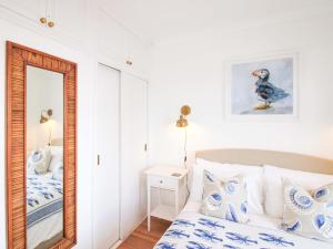 a bedroom with a blue and white bed and a mirror at 4 The Elms in Salcombe