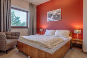 a bedroom with a bed and a chair and a window at Hotel Aviator - kompleks Silesia Ring in Kamień Śląski