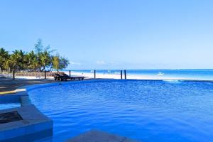 a large blue swimming pool next to a beach at Kusini Beach Cottages in Diani Beach