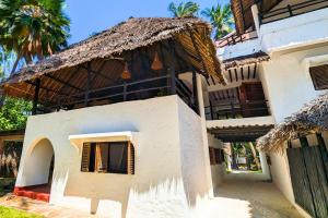 a building with a thatched roof and a gate at Kusini Beach Cottages in Diani Beach