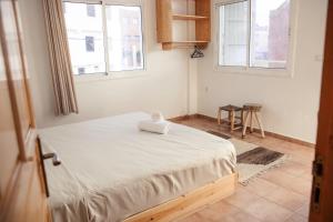 a bed in a room with two windows at Get Salty Guesthouse in Tamraght Ouzdar