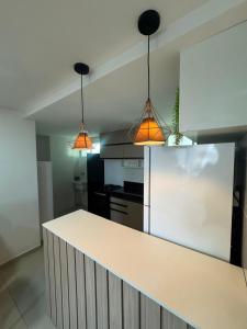 a kitchen with a white counter and three pendant lights at 2 quartos a 300m do mar do bessa in João Pessoa +6 photos